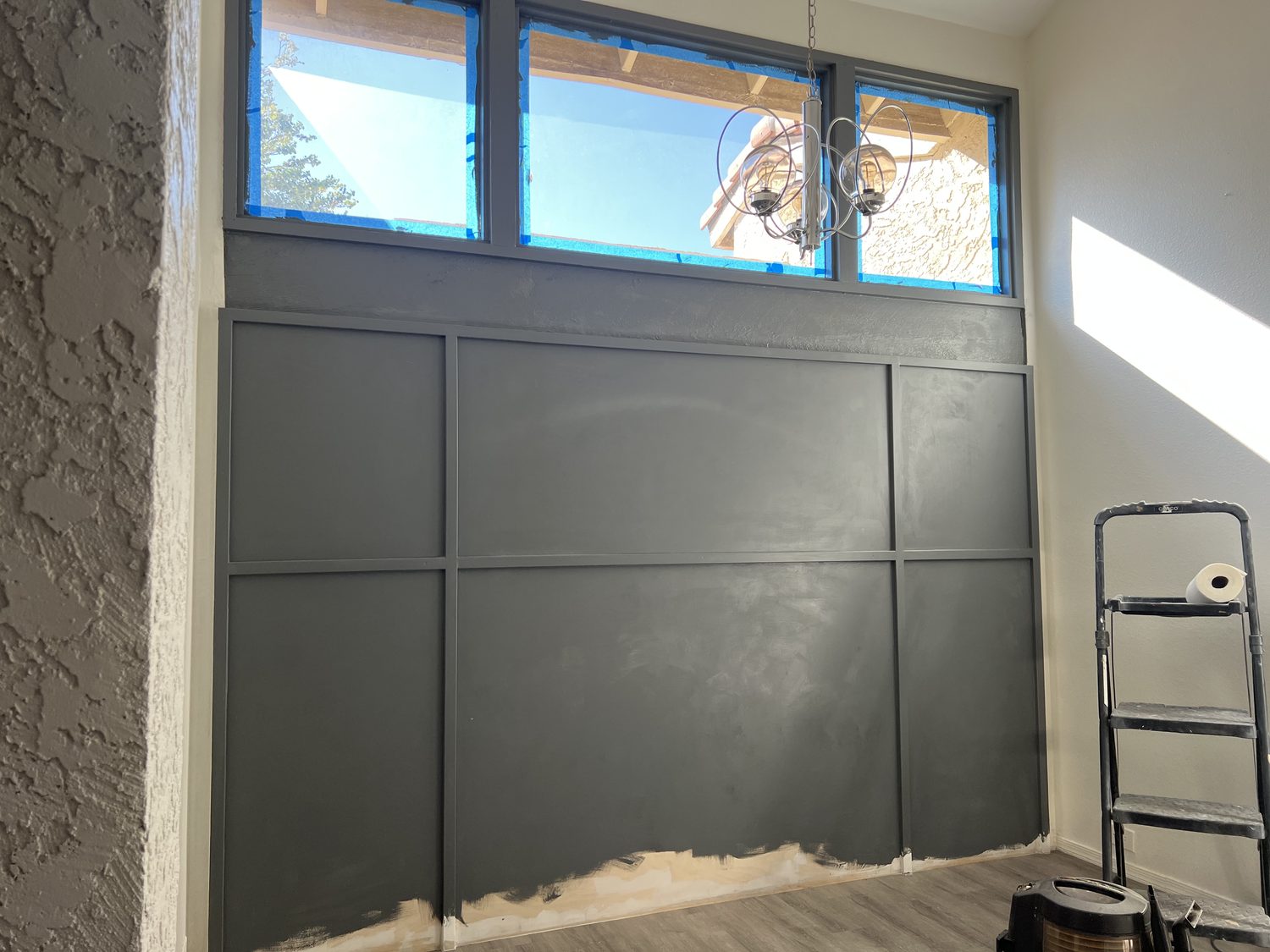 The paneled wall painted a deep charcoal with the transom windows masked off above