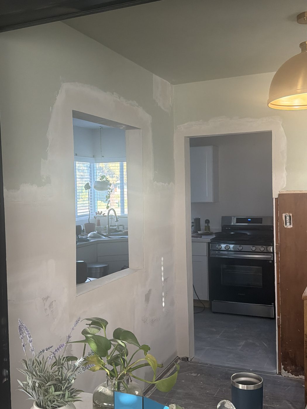 Same wall with new drywall hung, taped, and mudded smooth with finished pass through and doorway openings