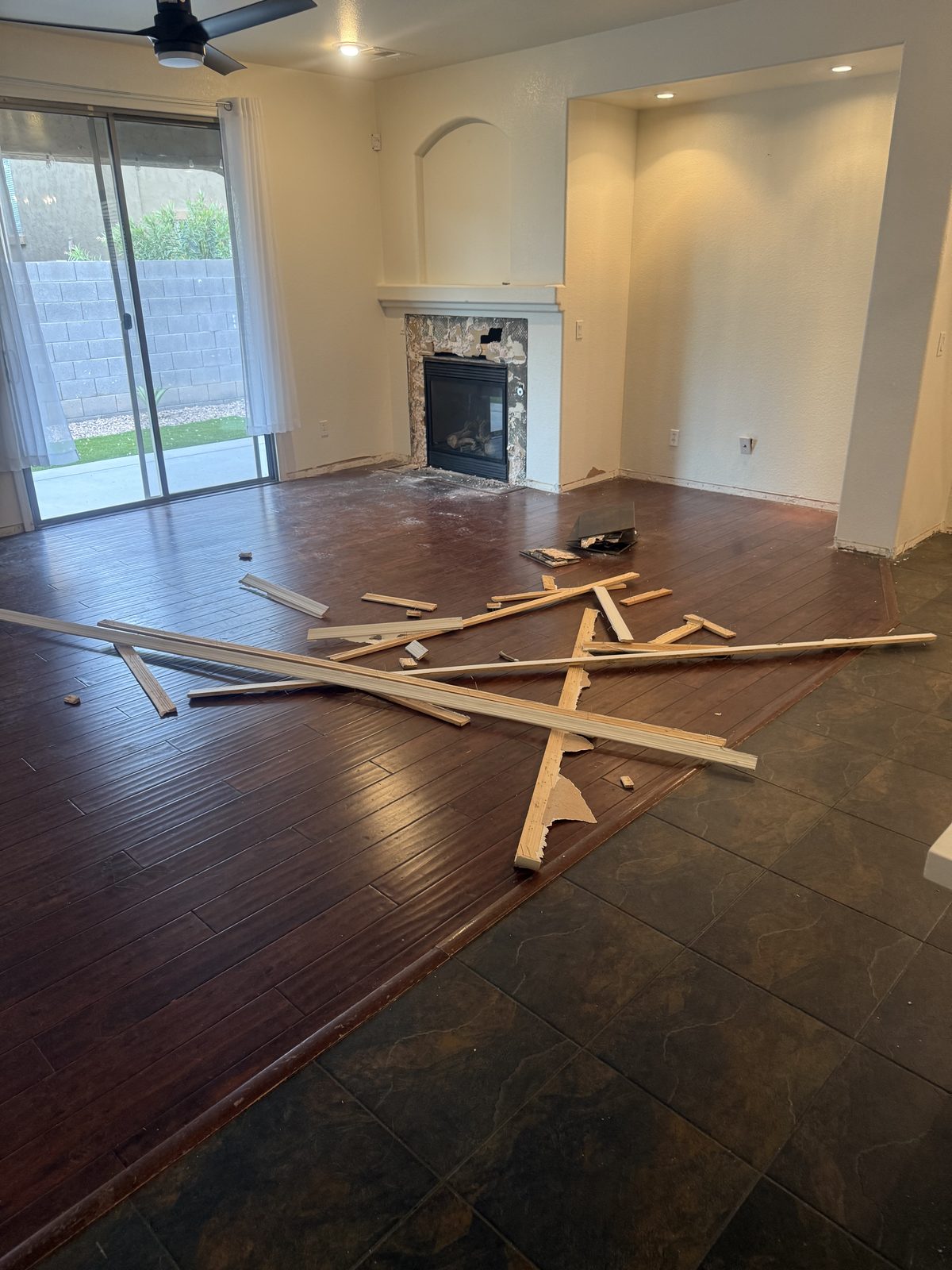 Living room with dark cherry engineered wood and dark slate tile, baseboards removed during demolition