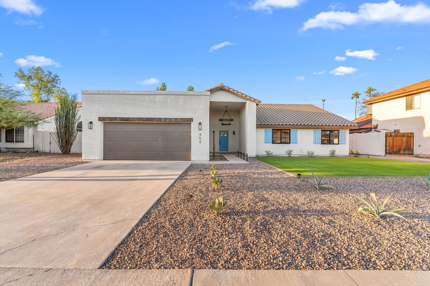 Renovated Mesa home with fresh stucco, new front door, desert landscaping, and lawn after renovation