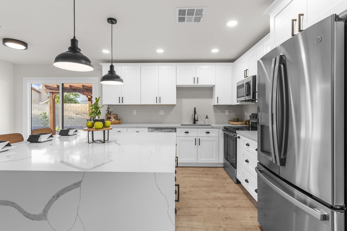 Renovated kitchen with white shaker cabinets, quartz waterfall island, and stainless appliances