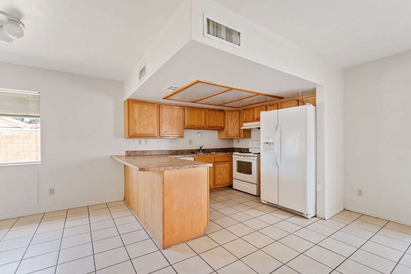 Original kitchen with oak cabinets, laminate counters, and white appliances before renovation