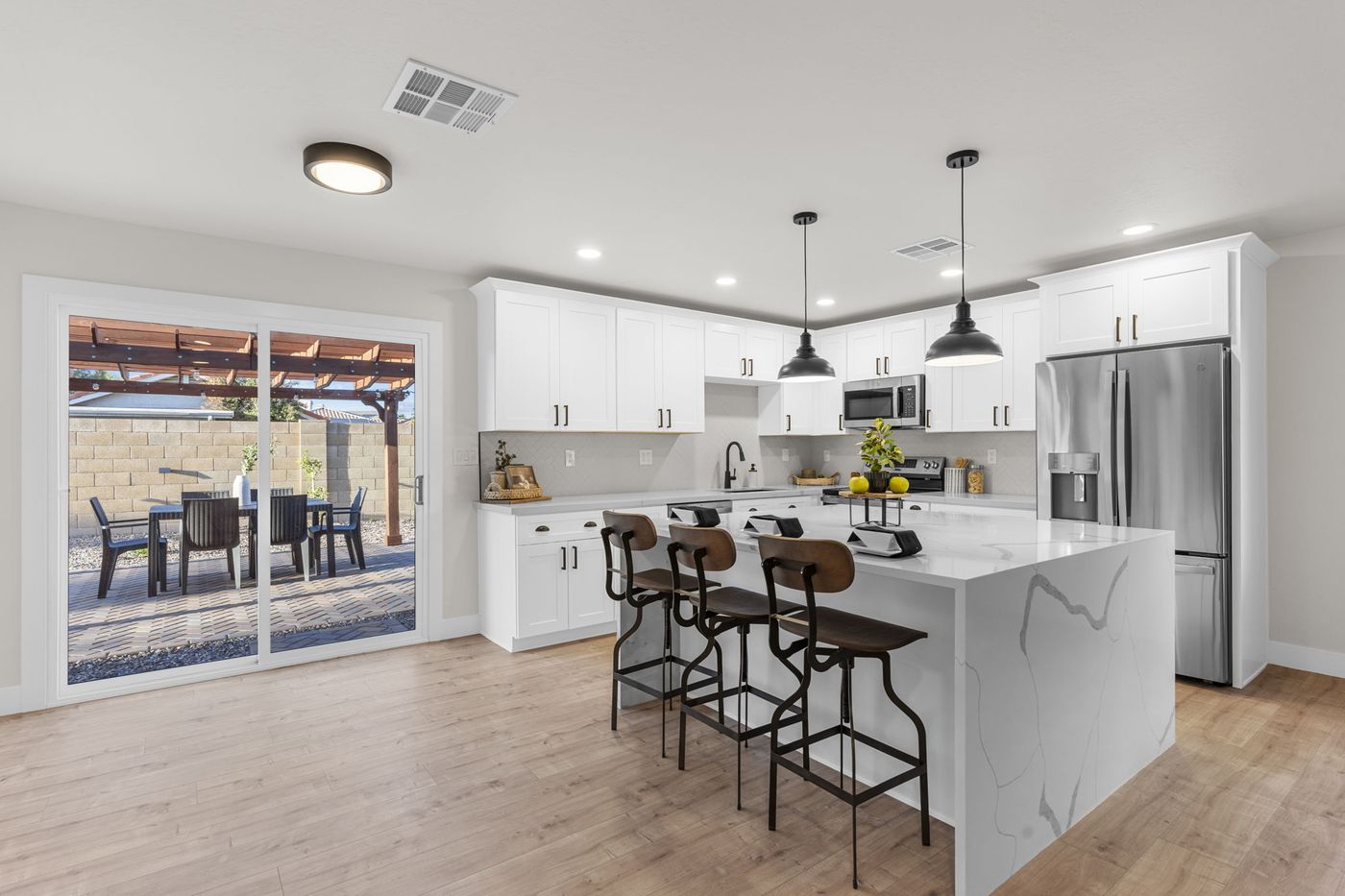 Open great room with wide plank flooring looking into the renovated white kitchen