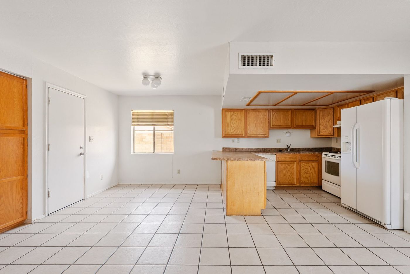 Great room with dated tile flooring looking toward the original oak kitchen before renovation