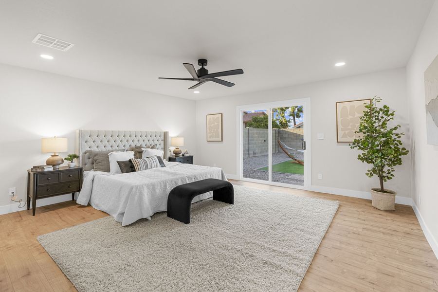 Primary bedroom with vaulted ceiling and wide plank flooring