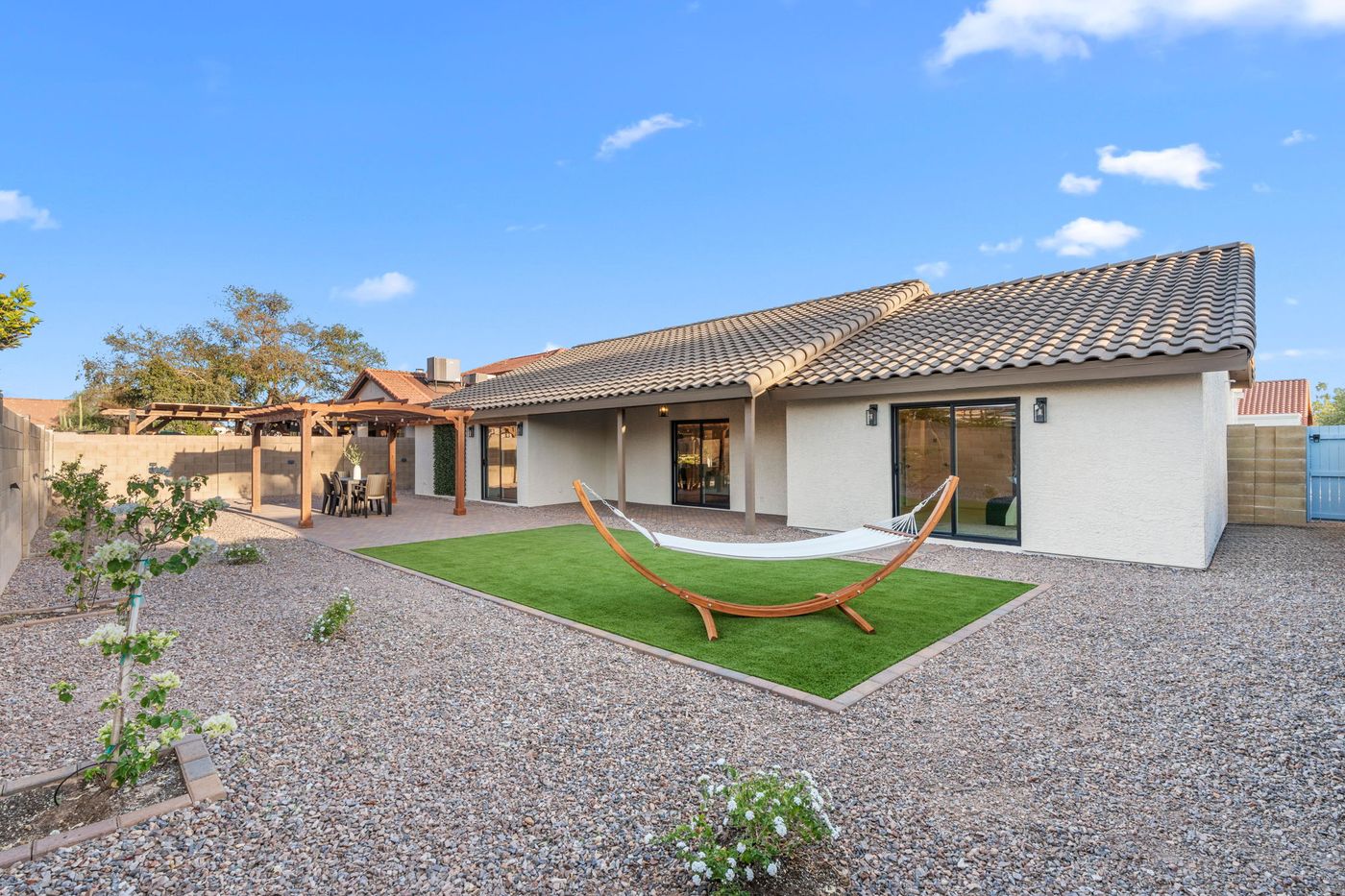 Renovated backyard with turf, desert landscaping, pavers, and a shade pergola