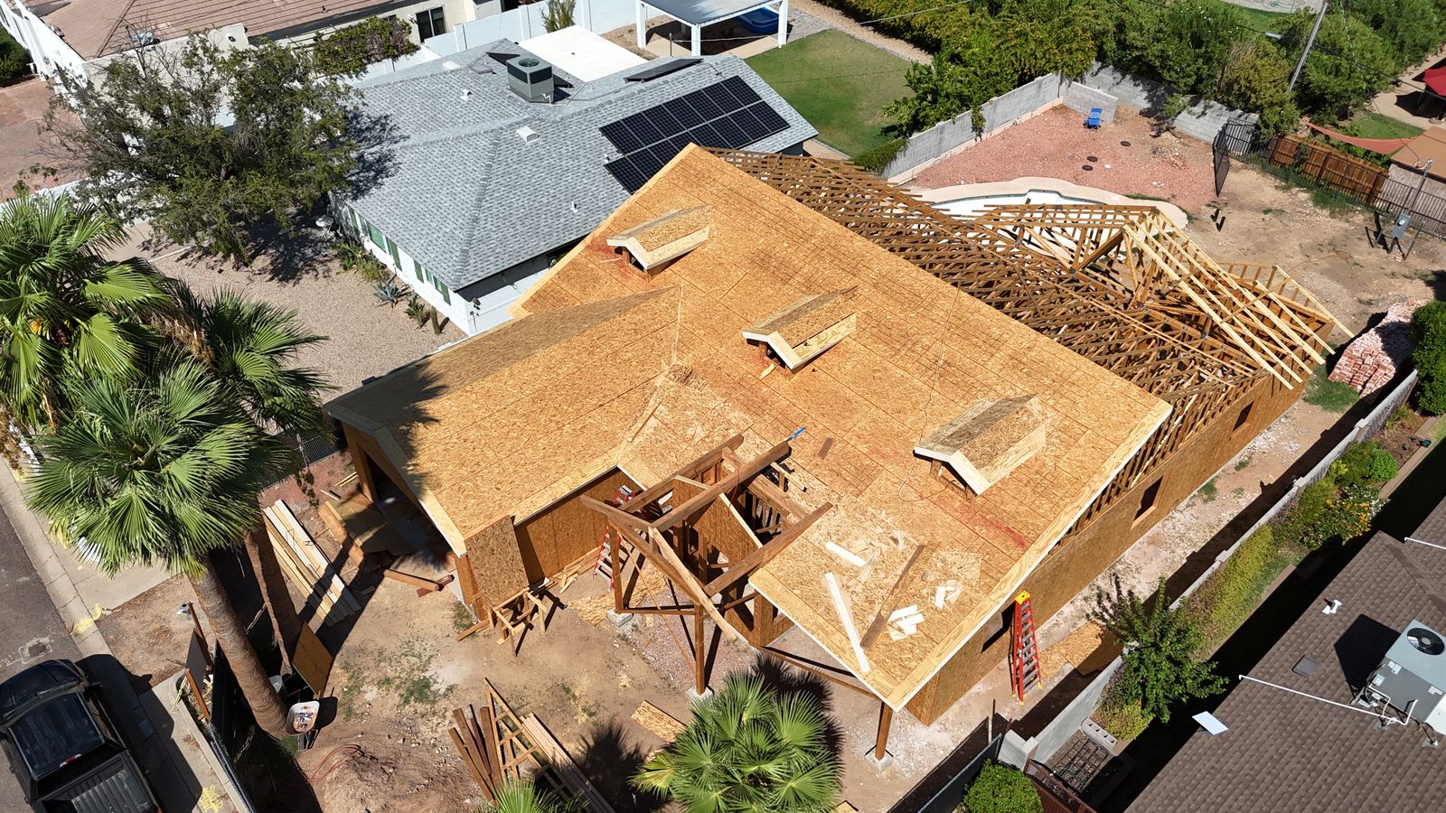 Rear aerial view of the framed home showing roof sheathing and open truss work