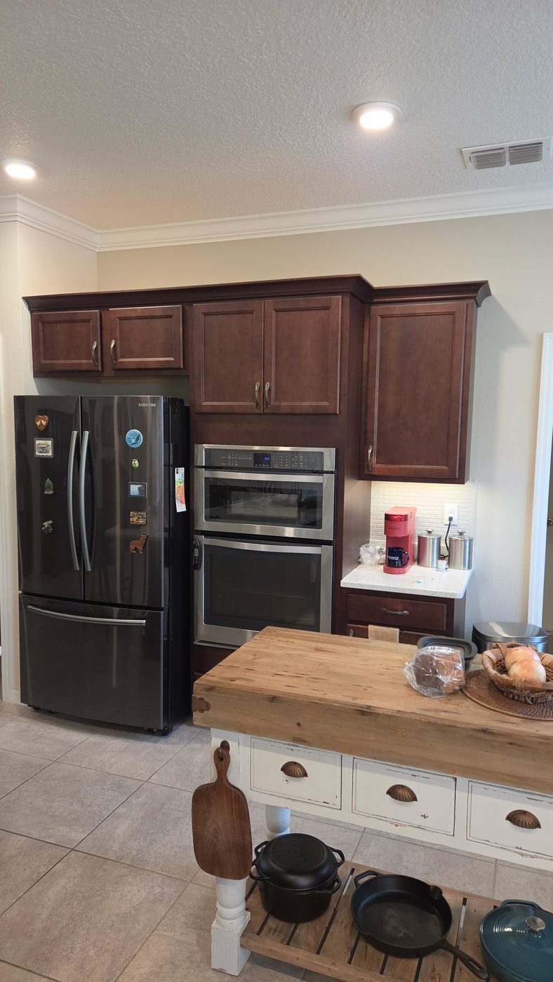 Kitchen with dark cherry stained cabinets around a double wall oven before refinishing